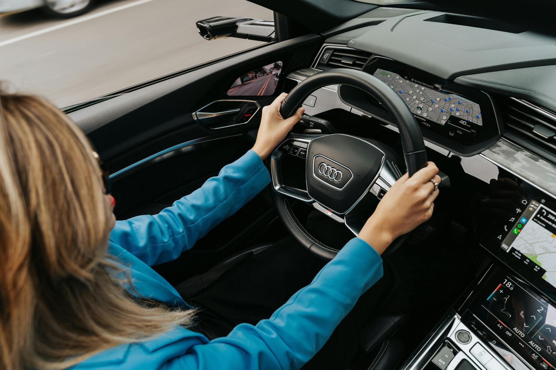 High angle view of a woman driving a modern Audi car, showcasing the dashboard and steering wheel.